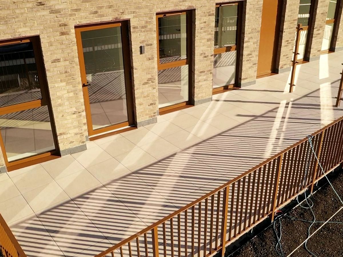 Large format porcelain paving laid across a roof terrace outside a row of glazed doors